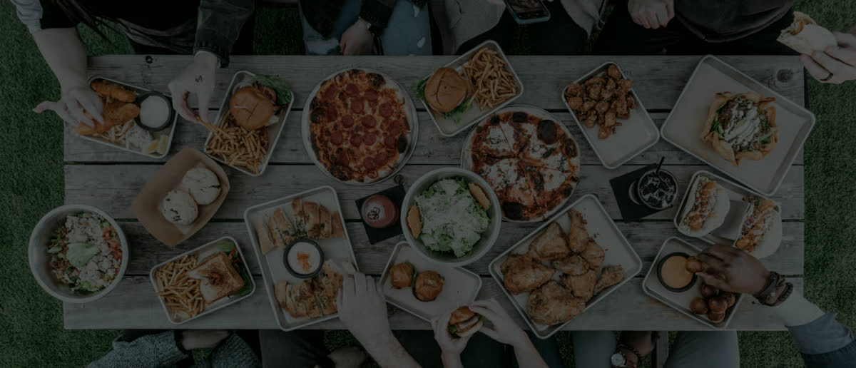 Un grupo comparte pizzas y platos en una mesa larga